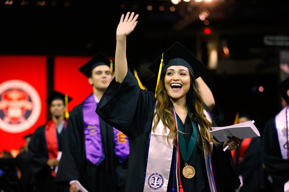 Graduating student in regalia waving